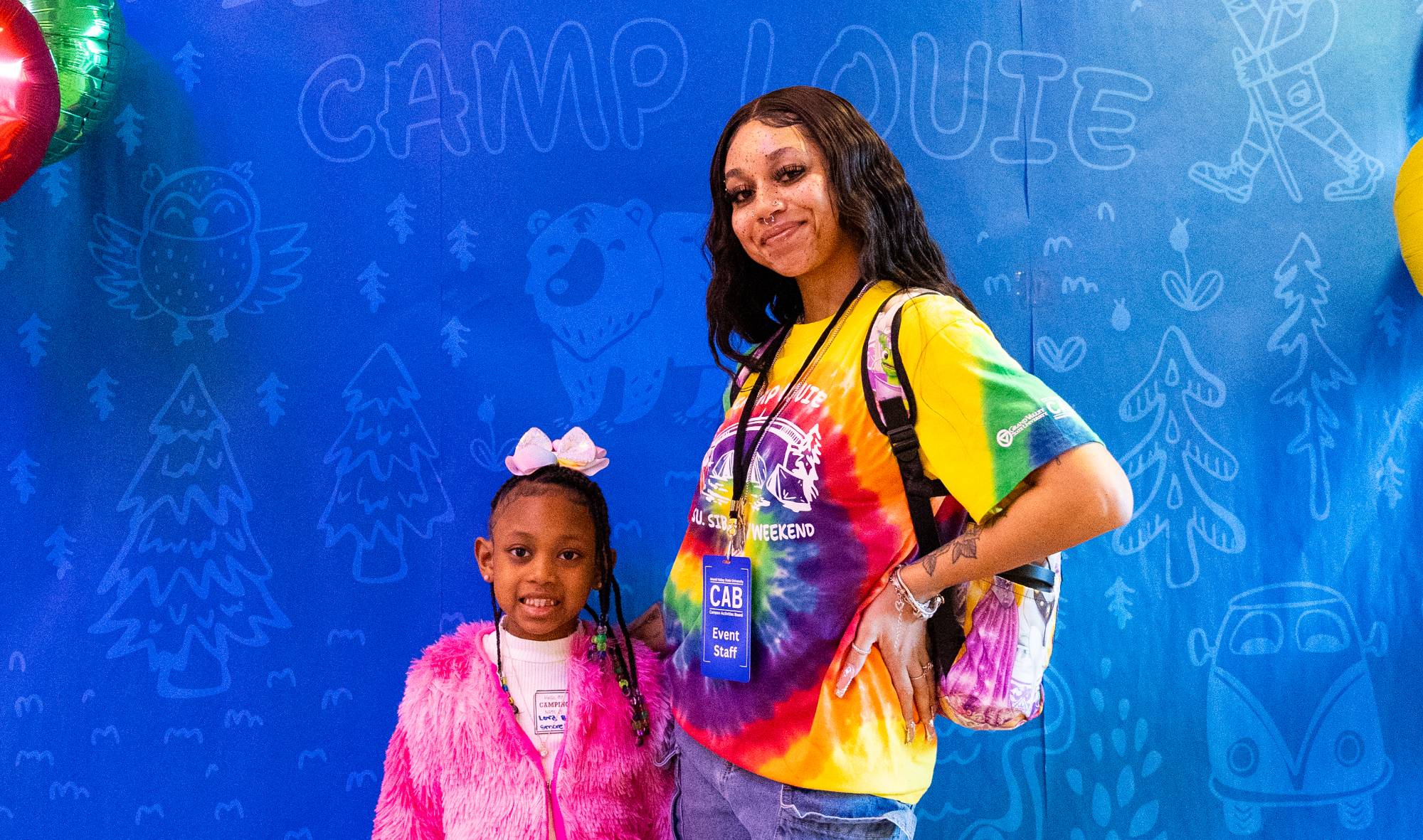 A student and a child posing in front of a backdrop